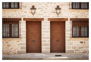 two wooden doors on a stone building with windows at El Casal de Nicolás in Fortanete