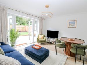 a living room with a blue couch and a table at Pine Cottage in Beccles
