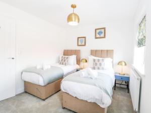 two twin beds in a room with white walls at Pine Cottage in Beccles