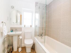 a bathroom with a toilet and a sink and a shower at Pine Cottage in Beccles +18 photos