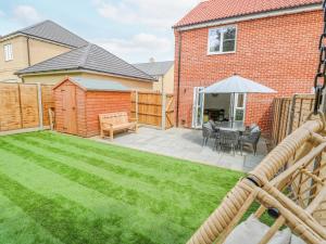 a backyard with a table and an umbrella at Pine Cottage in Beccles
