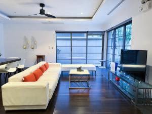 Una sala de estar con un sofá blanco y un televisor. en Perfect 2br Pool Villa In Residence Bangtao Beach4, en Bang Tao Beach