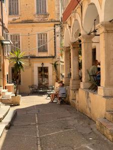 two people sitting in chairs outside of a building at THE CENTRIC Apt by LOC HOSPITALITY in Corfu Town