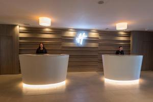 two women sitting at reception desks in a lobby at Holiday Inn - Glasgow Airport by IHG in Paisley