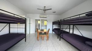 Zimmer mit 2 Etagenbetten sowie einem Tisch und Stühlen in der Unterkunft Accom KC's in Airlie Beach