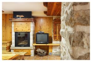 a living room with a tv and a stone wall at El Casal de Nicolás in Fortanete