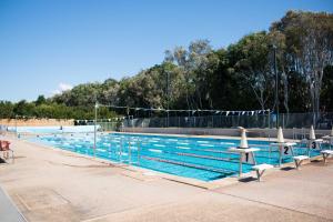 Short Stroll to White Sandy Beach في ساحة كاسوارينا: وجود مسبح بالطاولات والكراسي بجواره