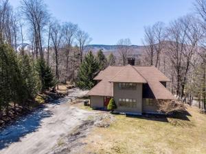 a house in the woods next to a river at Bearet - Hot Tub, Grill, Game Room, Fireplace in Killington