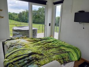 a bedroom with a bed and a large window at Au p'tit pré des salers in Hamois