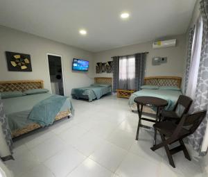 a bedroom with two beds and a table and a tv at Villa Tungara in Bejuco