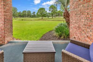 a patio with a bench and a field of grass at Elegant 3BR Condo - Magnolia North 101 in Myrtle Beach