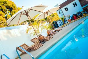 a pool with chairs and umbrellas next to a swimming pool at Odyssée Résidence in Mahajanga
