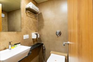 a bathroom with a sink and a toilet and a mirror at Hotel Embassy Park - BKC Mumbai in Mumbai