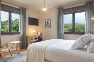 a bedroom with a bed and a desk and windows at Olivi1948 - Boutique Guest House in Usúrbil
