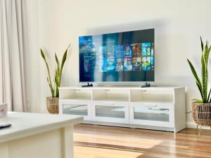 a living room with a tv on a white entertainment center at Heartwarming 3BR-Townhouse in Broadview