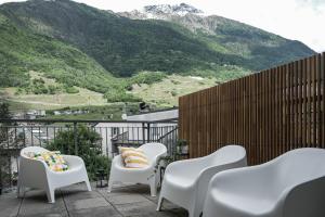 a balcony with white chairs and a view of mountains at DUPLEX with Terrace - 6 min walk to Bernina Express in Tirano