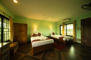 a hotel room with two beds and green walls at Wild Adventure Resort in Sauraha