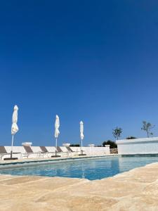 a swimming pool with chairs and a blue sky at Masseria Purgatorio in Fasano