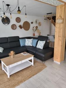 a living room with a black couch and a table at Au cœur de la nature Le cerf in Saint-Vincent-Jalmoutiers