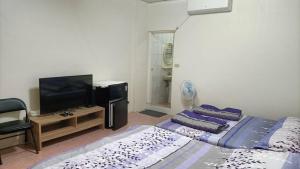 a living room with two beds and a flat screen tv at 頭城旅宿 in Toucheng