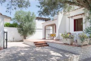 a white house with a patio with stairs and plants at Villa Antonella con Piscina nel Boomerang Village a Torre Colimena in Torre Colimena