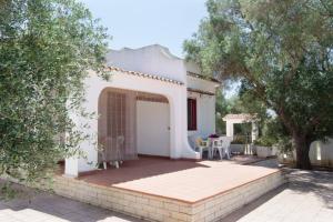 a white house with a patio and a table at Villa Antonella con Piscina nel Boomerang Village a Torre Colimena in Torre Colimena