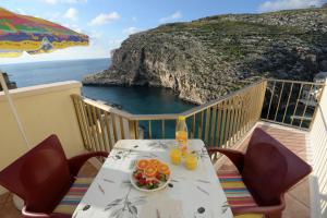 a table with a plate of fruit on a balcony at Avalon - Bellevue Gozo in Xlendi
