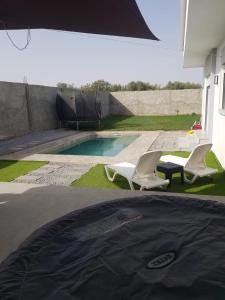 twee witte stoelen naast een zwembad bij Villa Kenza in Douar el Khima +1 foto