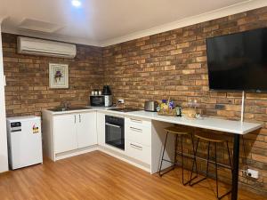 Eine Küche mit weißer Arbeitsplatte und einem Fernseher an einer Backsteinwand in der Unterkunft Darcy’s Ranch in Bathurst