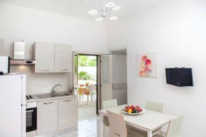 a kitchen with a table with a bowl of fruit on it at Casa Giuditta con piscina a 110 mt dalla spiaggia di Punta Prosciutto in Punta Prosciutto