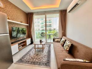 a living room with a couch and a tv at PALMTREE BREEZE Condo in Amazon Residence in Jomtien Beach