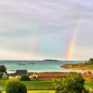 un arc-en-ciel sur une masse d'eau avec une maison dans l'établissement Ty Koad, à Lanmodez