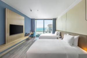 a hotel room with two beds and a flat screen tv at Awaken Da Nang Hotel in Danang