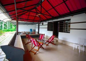 un gruppo di sedie rosse sedute sotto un tetto rosso di Wildside Wayanad a Wayanad