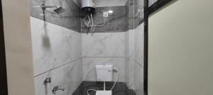 ein Badezimmer mit Toilette mit Marmorwänden und Dusche in der Unterkunft TARA Guest House in Ujjain