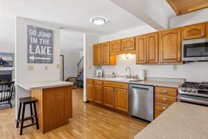 a kitchen with wooden cabinets and stainless steel appliances at Lakefront Getaway- Hot Tub, Firepit & Fireplaces! home in Shoreview