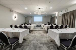 a conference room with white tables and chairs and a screen at The Originals Boutique, Hôtel Le Pariou, Issoire in Issoire +101 photos