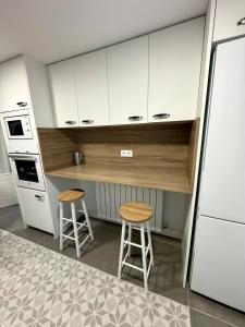 a kitchen with white cabinets and two stools at El Torreón de Muro in Boltaña