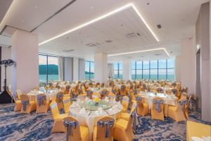 a banquet hall with tables and yellow chairs at Awaken Da Nang Hotel in Danang