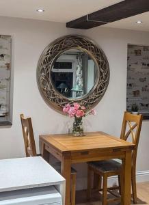 a table with a mirror and a vase with flowers on it at Little Sycamore in Lyminge