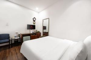 a bedroom with a white bed and a desk and a mirror at A25 Hotel - 12 Liên Trì in Hanoi