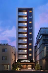 a tall building with lights on in a city at Tanimachi LUXE HOTEL in Osaka