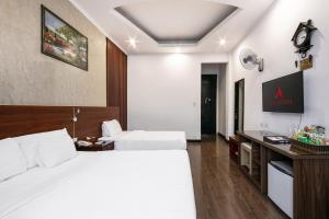 a hotel room with two beds and a clock on the wall at A25 Hotel - 12 Liên Trì in Hanoi