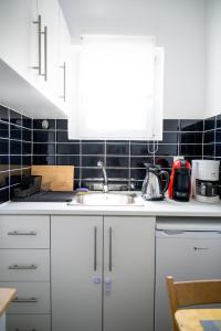 a kitchen with white cabinets and a sink at Hygge Home at Trikala in Tríkala