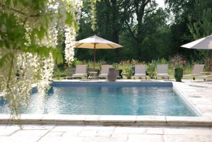 a swimming pool with chairs and umbrellas at Bastide Rose in Le Thor