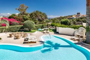 a pool with chaise lounge chairs and a resort at Hotel Corallaro in Santa Teresa Gallura