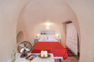 a bedroom with a red bed and a table with a fan at Amelie Canaves Finikia in Foinikiá