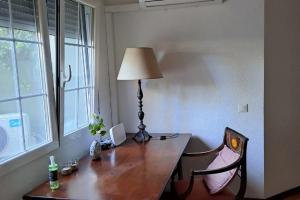 a desk with a lamp and a chair next to a window at Casa Cerca del Aeropuerto y del Jarama in Santo Domingo +8 photos