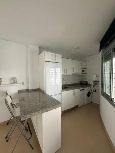 a kitchen with white cabinets and a white refrigerator at Turquesa 8 in Zahara de los Atunes +11 photos