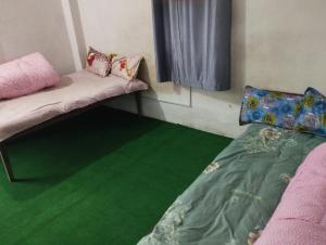 una camera con pavimento verde, letto e finestra di Tharu COOP Homestay in Sauraha -Chitwan a Sauraha Altre 7 foto
